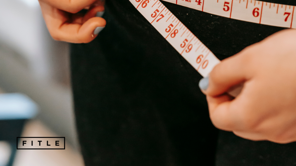 Femme qui se mesure son tour de taille avec un ruban.